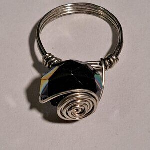 silver color wire ring with round dark bead with shiny rainbow effect in middle